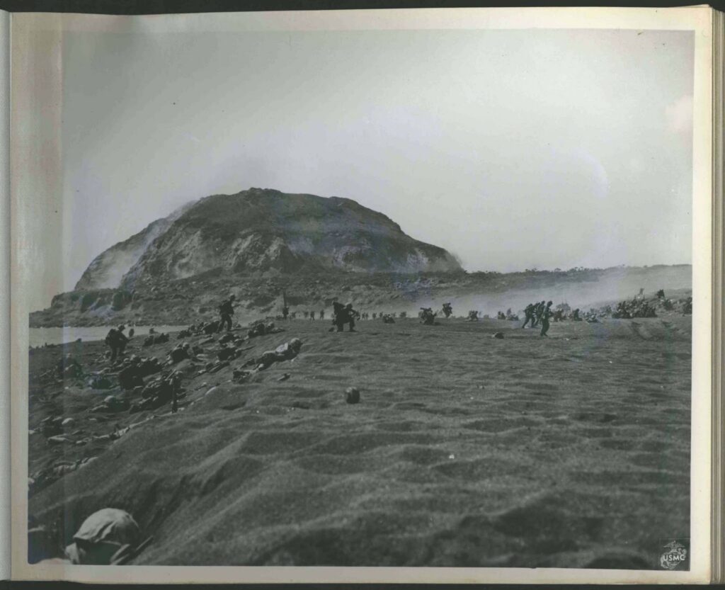 US Marines move toward Mount Suribachi across the black sandy beaches of Iwo Jima