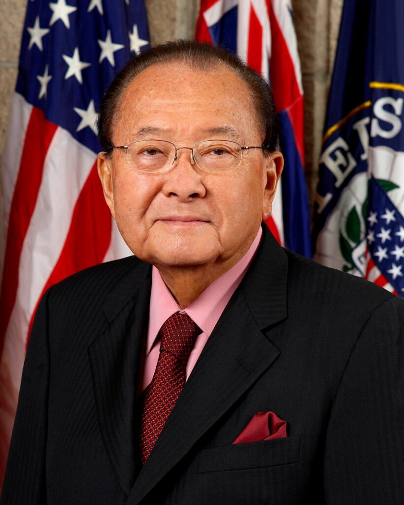 Official color portrait of Senator Daniel Inouye wearing a dark suit and patterned tie, posed against a neutral studio background.