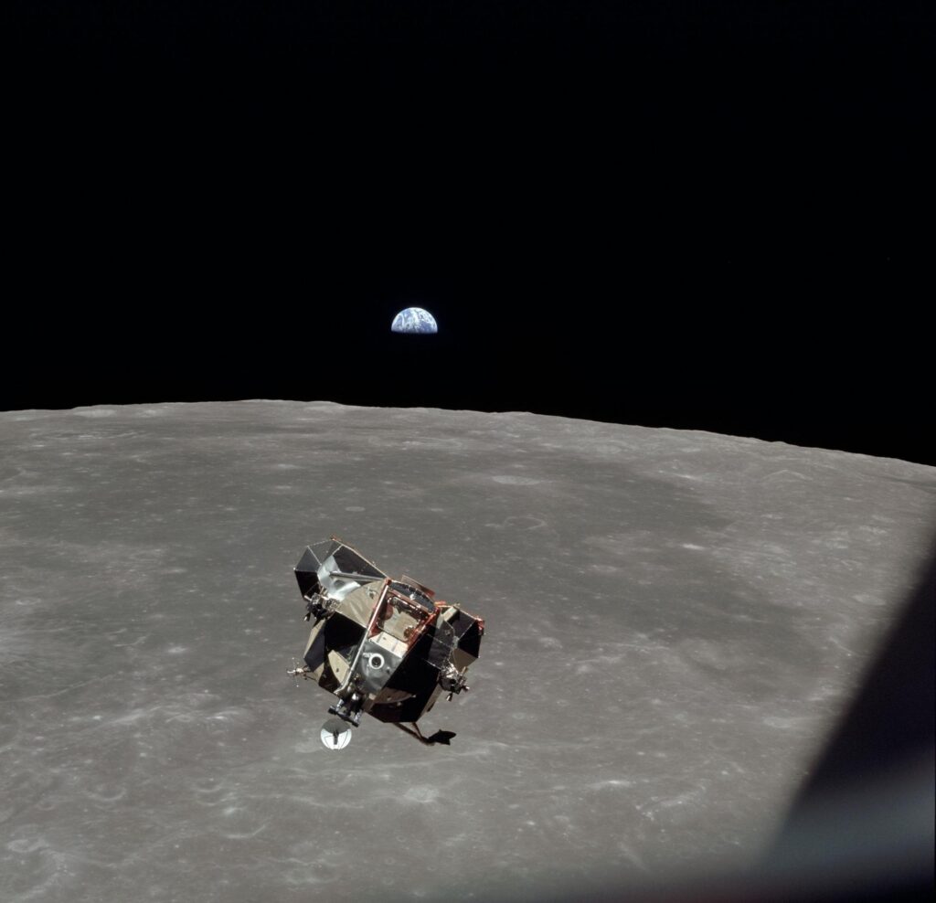 Photograph of Earth rising above the Moon's horizon as seen from Apollo 11 in lunar orbit, with the gray lunar surface in the foreground