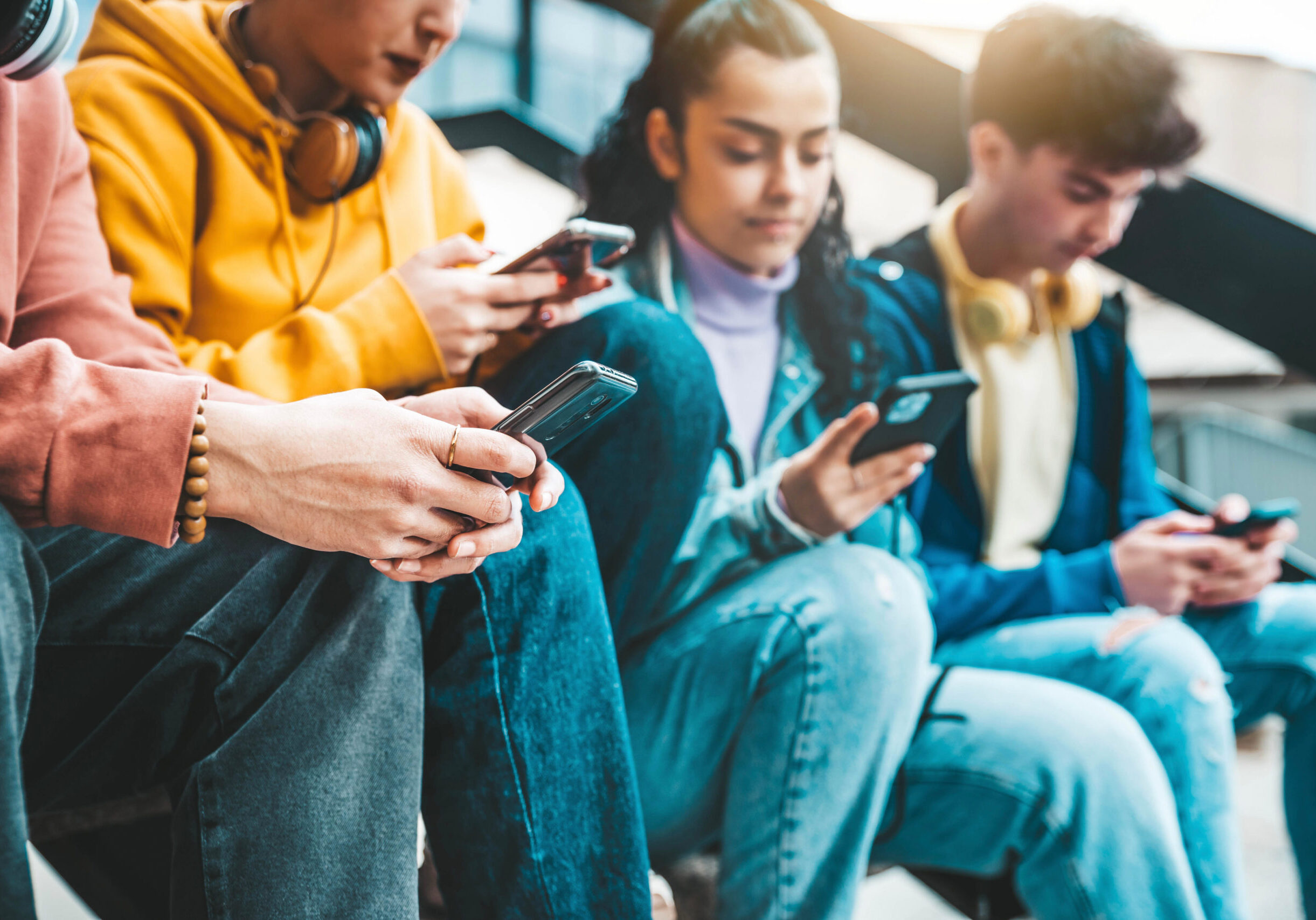 Millennial friends watching smart mobile phone device outside - Young people using cellphones playing on social media platforms - Technology addiction concept
